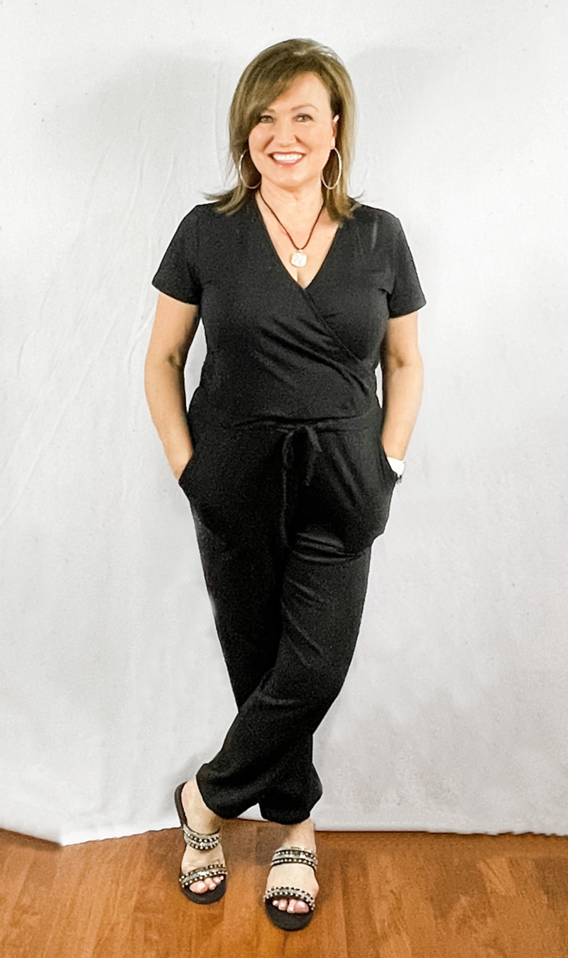 Woman in black jumpsuit with black studded sandals.