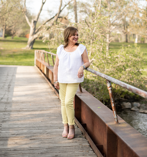 A woman at a park wearing yellow jeans and a white top/