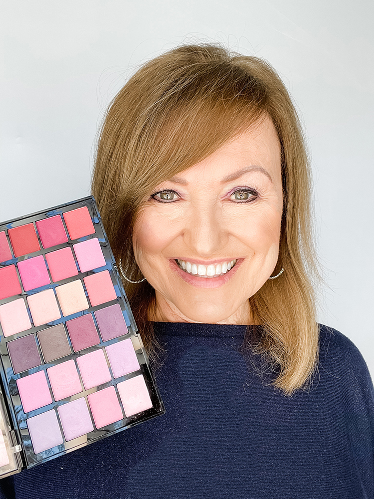 Women with hazel eyes holding up purple eyeshadow palette for best eyeshadow for your eye color.